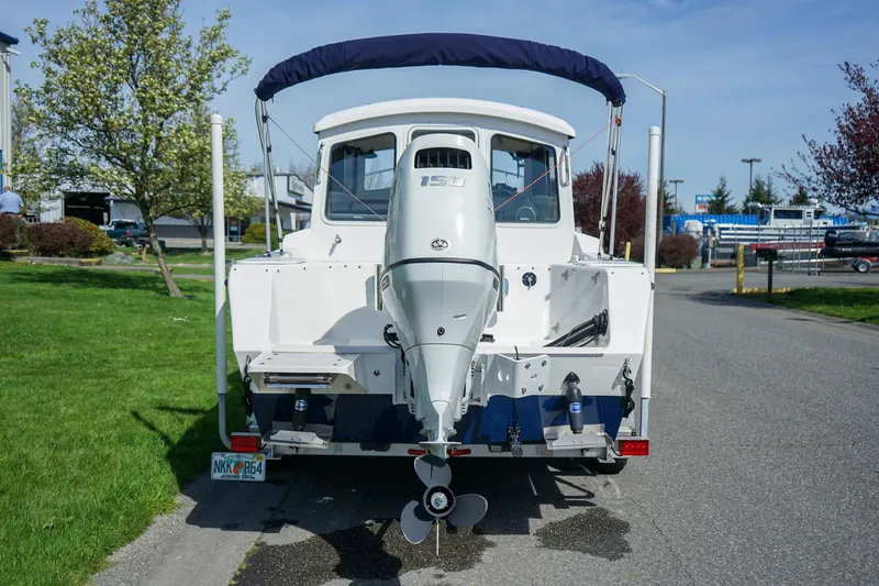 Slide: The Image of 2024 C-Dory 23' Venture Sport boat with outboard motor, parked on a sunny day. - 5
