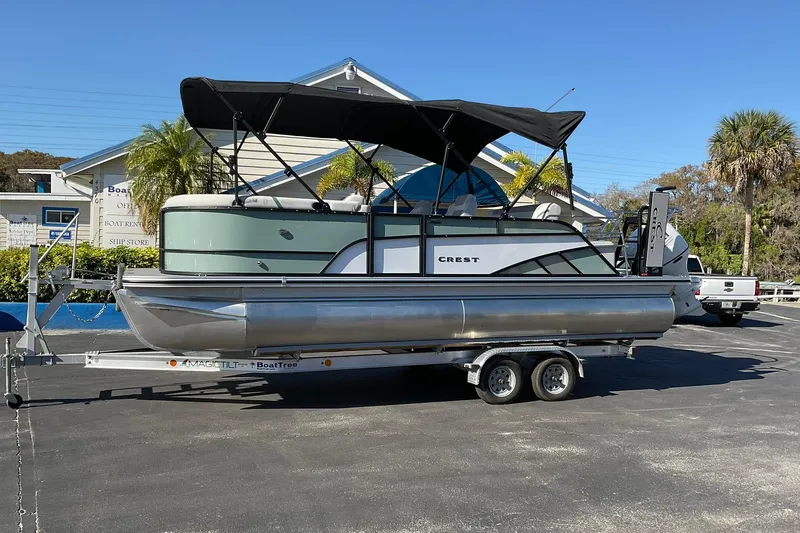 The Image of 2026 Crest Conquest 230 SLSC pontoon boat on trailer, parked outdoors. - 0