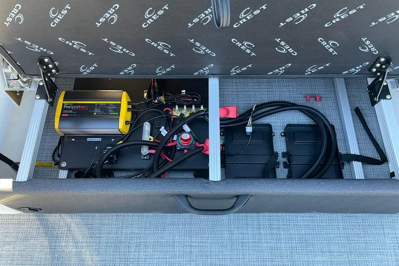 Slide: The Image of Interior view of 2026 Crest Conquest 230 SLSC boat's battery compartment with wiring and charger. - 27