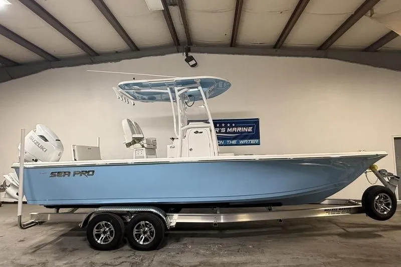 The Image of 2026 Sea Pro 250 Bay boat in showroom, light blue hull, on trailer. - 0