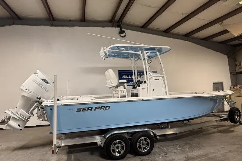 Slide: The Image of 2026 Sea Pro 250 Bay boat in a garage, featuring a Suzuki outboard motor. - 2