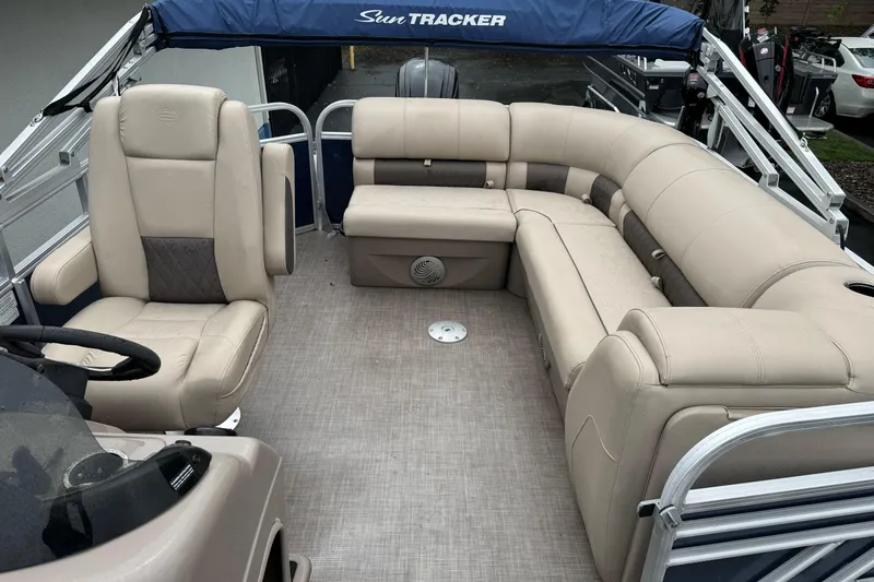 Slide: The Image of 2021 Sun Tracker Party Barge 20 DLX interior with beige seating and steering console. - 12