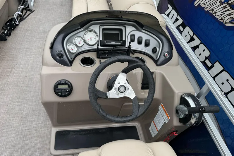 Slide: The Image of 2021 Sun Tracker Party Barge 20 DLX steering console with gauges and controls. - 14