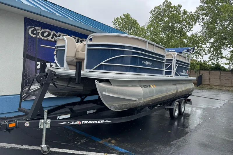 Slide: The Image of 2021 Sun Tracker Party Barge 20 DLX pontoon boat on trailer, parked outdoors. - 2
