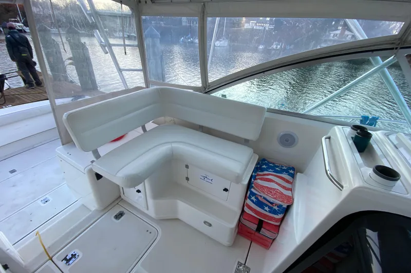 Slide: The Image of 2000 Pursuit 3400 Express boat interior with white seating and American flag cooler. - 16