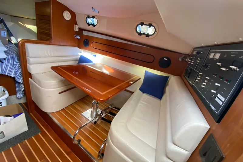 Slide: The Image of Interior of 2000 Pursuit 3400 Express boat with wood table and white seating. - 21
