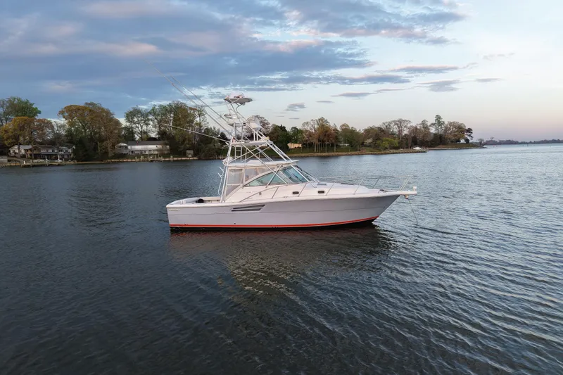 Slide: The Image of 2000 Pursuit 3400 Express boat on calm water with scenic shoreline background. - 26