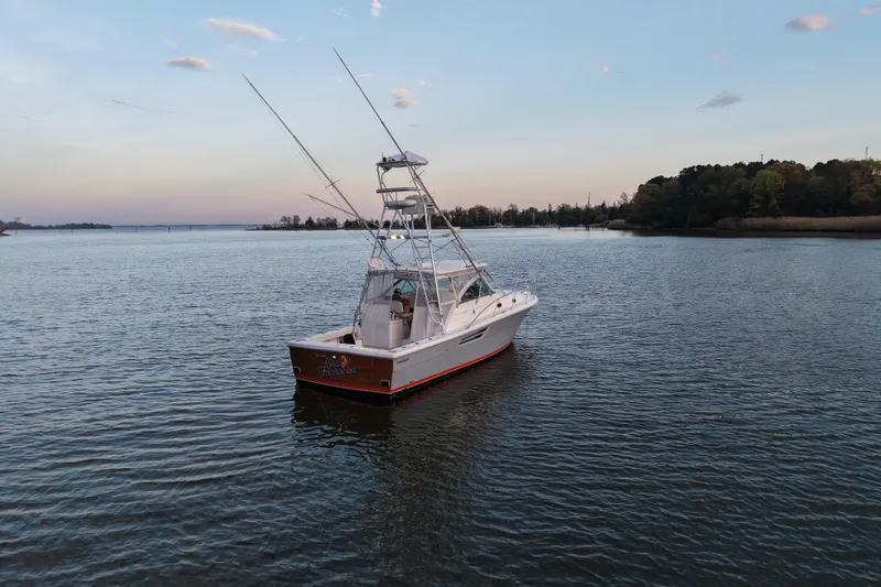 Slide: The Image of 2000 Pursuit 3400 Express boat on calm water at sunset, with fishing rods visible. - 29