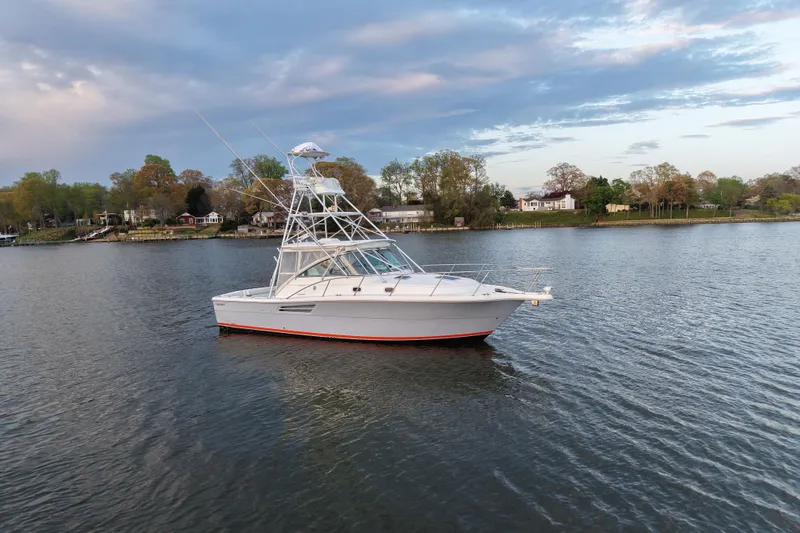 Slide: The Image of 2000 Pursuit 3400 Express boat on calm water with scenic shoreline background. - 33
