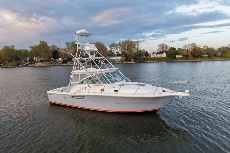 Slide: The Image of 2000 Pursuit 3400 Express boat on calm water under a cloudy sky. - 34