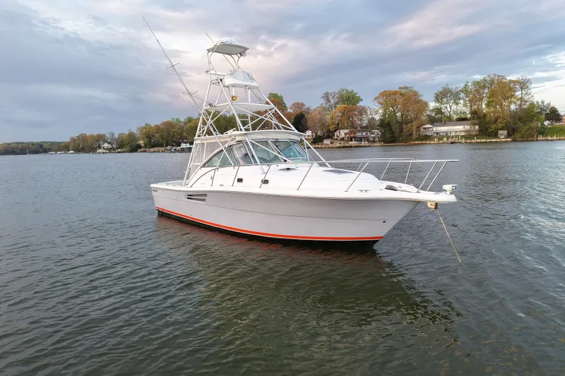 Slide: The Image of 2000 Pursuit 3400 Express boat on calm water, with scenic shoreline background. - 35