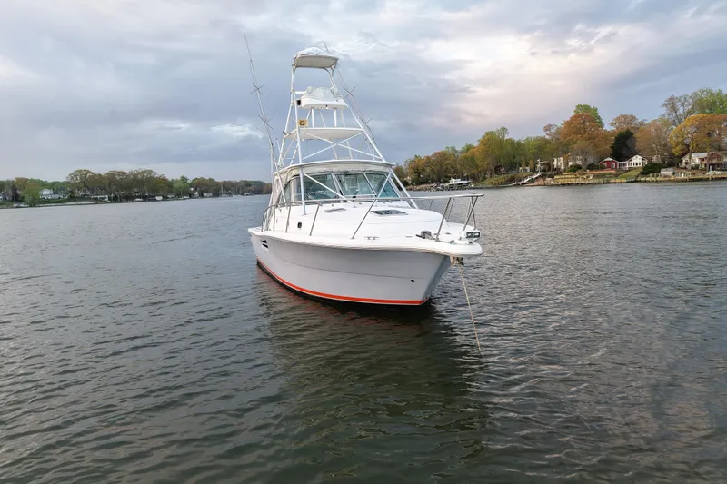 Slide: The Image of 2000 Pursuit 3400 Express boat anchored on a calm lake with scenic shoreline. - 8