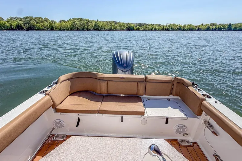 Slide: The Image of 2021 Sea Hunt Ultra 255 SE boat interior with tan seating on a calm lake. - 11