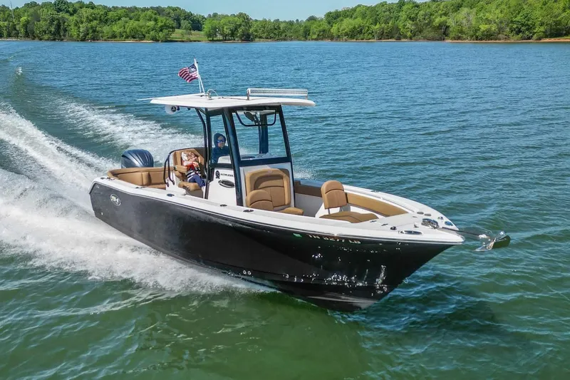 Slide: The Image of 2021 Sea Hunt Ultra 255 SE boat cruising on a lake with lush green shoreline. - 2