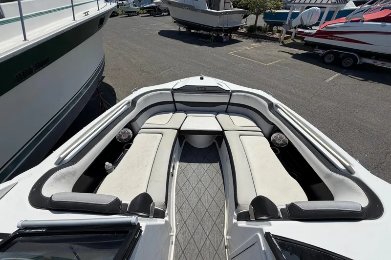 Slide: The Image of 2020 Yamaha Boats 275SD bow seating area with cushioned benches, docked among other boats. - 15