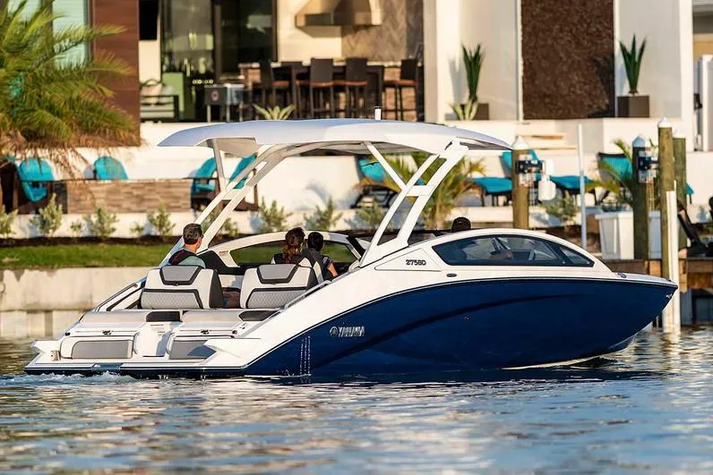 Slide: The Image of Manufacturer Provided Image: 2020 Yamaha Boats 275SD cruising on water near a modern waterfront property. - 3