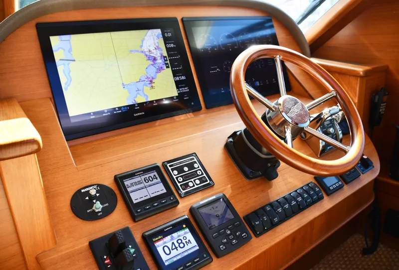 Slide: The Image of 2020 Palm Beach Motor Yachts PB52 helm with navigation screens and wooden steering wheel. - 31
