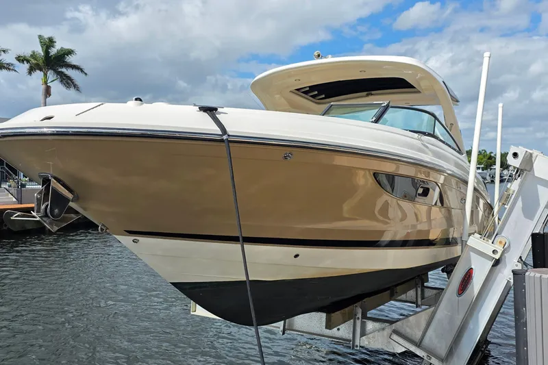The Image of 2015 Sea Ray SLX 350 boat on lift, docked by palm trees under cloudy sky. - 0