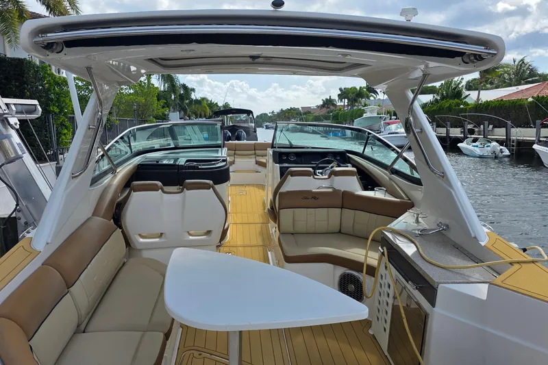 Slide: The Image of 2015 Sea Ray SLX 350 boat interior with seating, table, and helm, docked by a canal. - 16