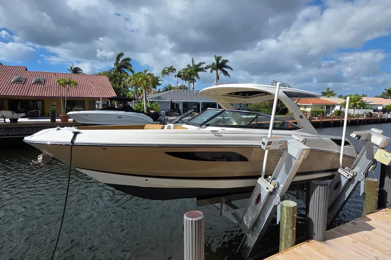 Slide: The Image of 2015 Sea Ray SLX 350 boat docked on a lift, surrounded by waterfront homes. - 2