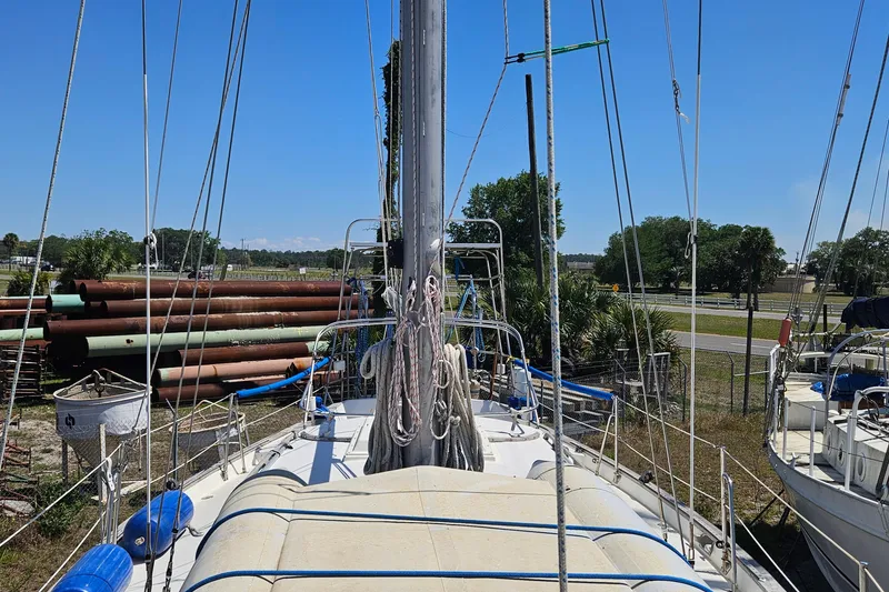 Slide: The Image of 1979 Morgan 382 sailboat on land, surrounded by trees and industrial pipes. - 12