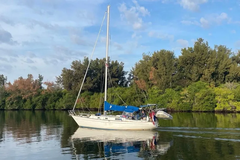 Slide: The Image of 1979 Morgan 382 sailboat on calm water, surrounded by lush greenery and clear skies. - 2