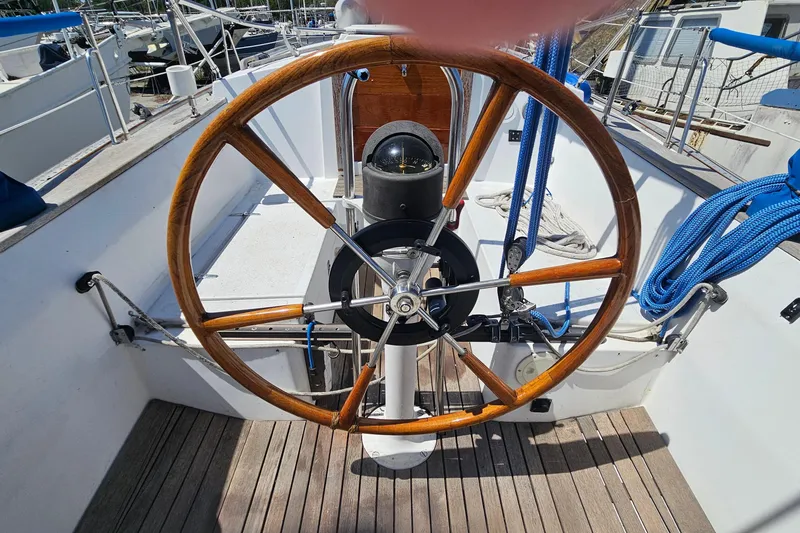 Slide: The Image of Wooden steering wheel of a 1979 Morgan 382 sailboat, featuring nautical ropes and compass. - 20