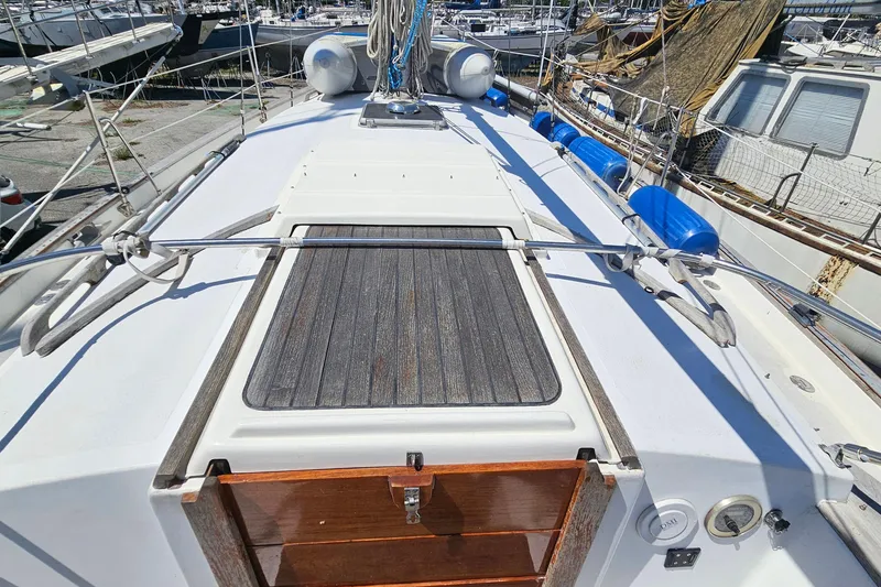 Slide: The Image of 1979 Morgan 382 sailboat deck with wooden hatch and marina background. - 22