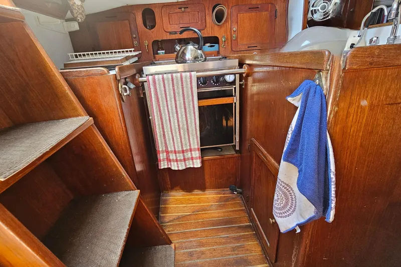 Slide: The Image of Interior of a 1979 Morgan 382 sailboat galley with wooden cabinetry and stove. - 25