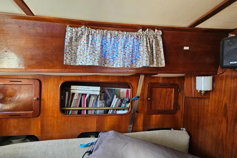 Slide: The Image of Interior of a 1979 Morgan 382 sailboat with wooden cabinetry and nautical-themed curtains. - 37