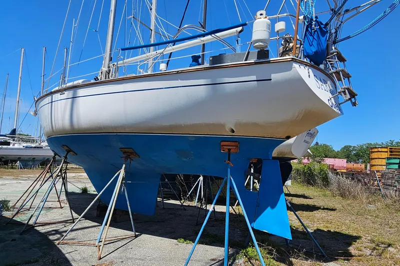 Slide: The Image of 1979 Morgan 382 sailboat on stands, blue hull, in a boatyard under clear sky. - 5