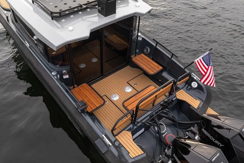 Slide: The Image of 2023 Arksen 30 Adventure boat with teak deck, American flag, and Mercury engines on water. - 20