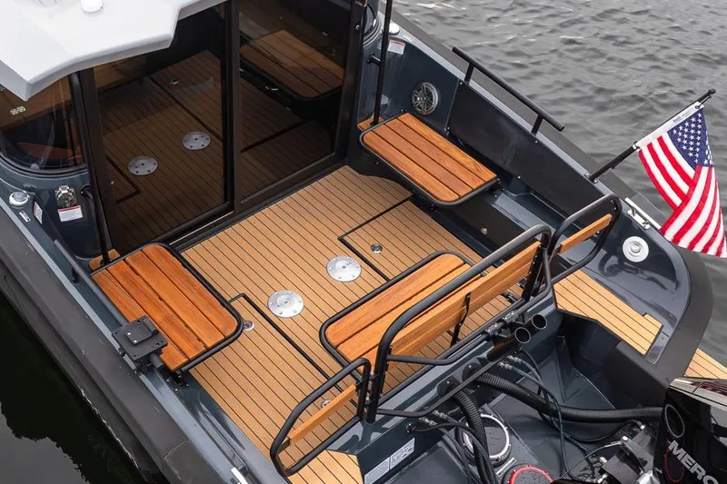 Slide: The Image of 2023 Arksen 30 Adventure boat deck with wooden seating and American flag. - 21