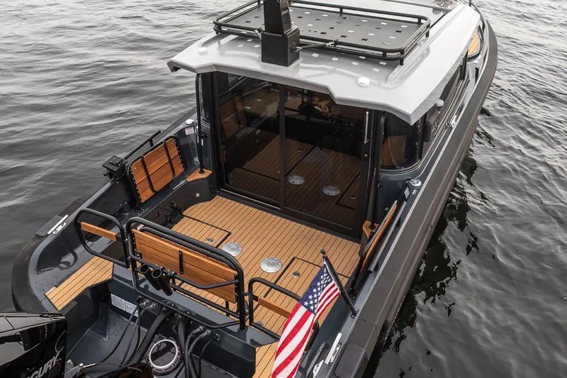 Slide: The Image of 2023 Arksen 30 Adventure boat with wooden deck, American flag, and sleek design on water. - 23