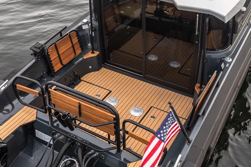 Slide: The Image of 2023 Arksen 30 Adventure boat with teak deck and American flag on calm water. - 24