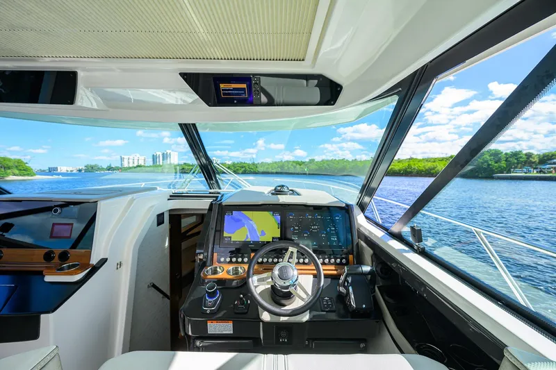 Slide: The Image of 2022 Tiara Yachts 43 LE helm with modern navigation system and scenic waterway view. - 37