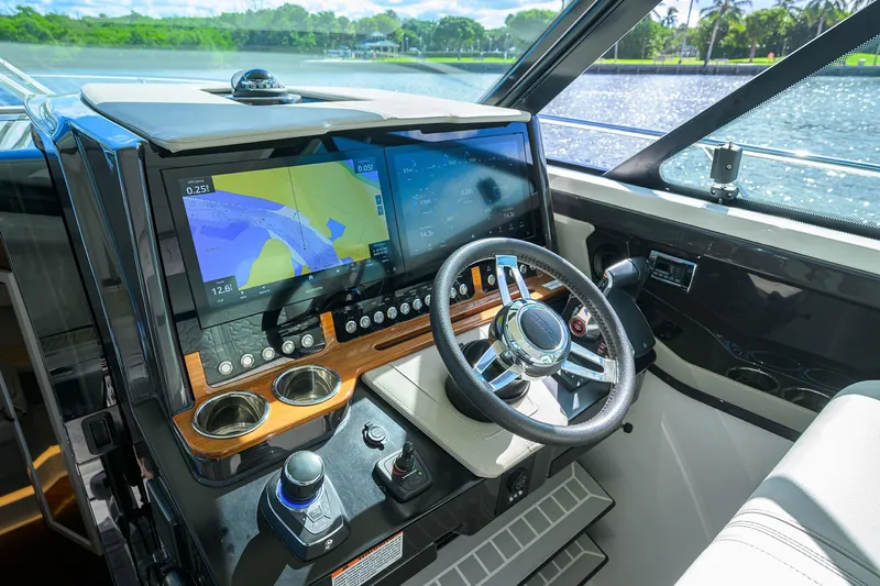 Slide: The Image of 2022 Tiara Yachts 43 LE helm with advanced navigation displays and steering wheel. - 38