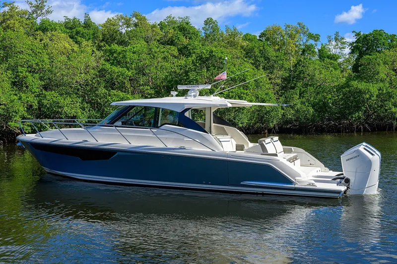 Slide: The Image of 2022 Tiara Yachts 43 LE luxury boat on calm water, surrounded by lush greenery. - 57