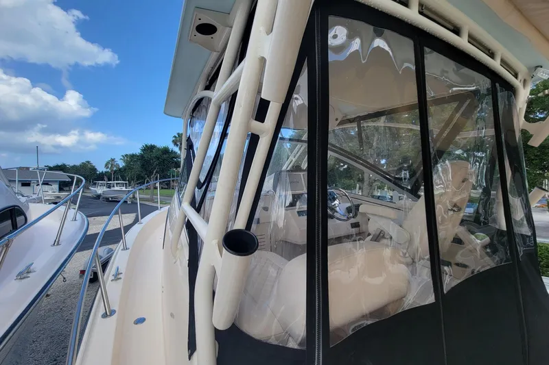 Slide: The Image of 2023 Grady-White Marlin 300 boat with clear enclosure, docked under blue sky. - 12