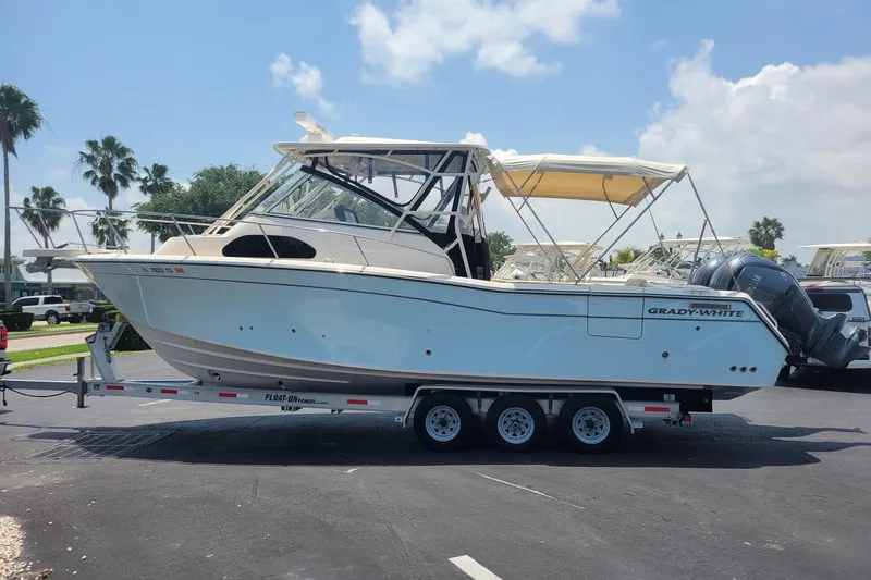 Slide: The Image of 2023 Grady-White Marlin 300 boat on trailer, parked outdoors under clear sky. - 5