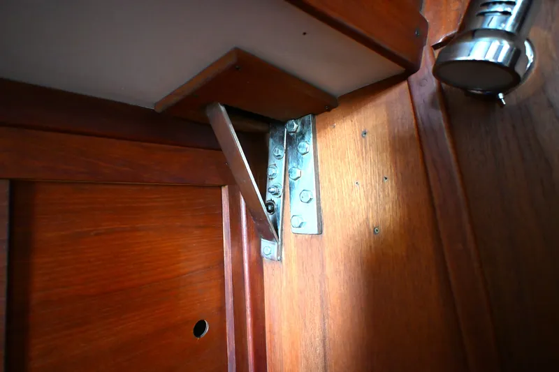 Slide: The Image of Wooden interior detail of a 1980 Tartan 37 sailboat, featuring a metal hinge. - 52