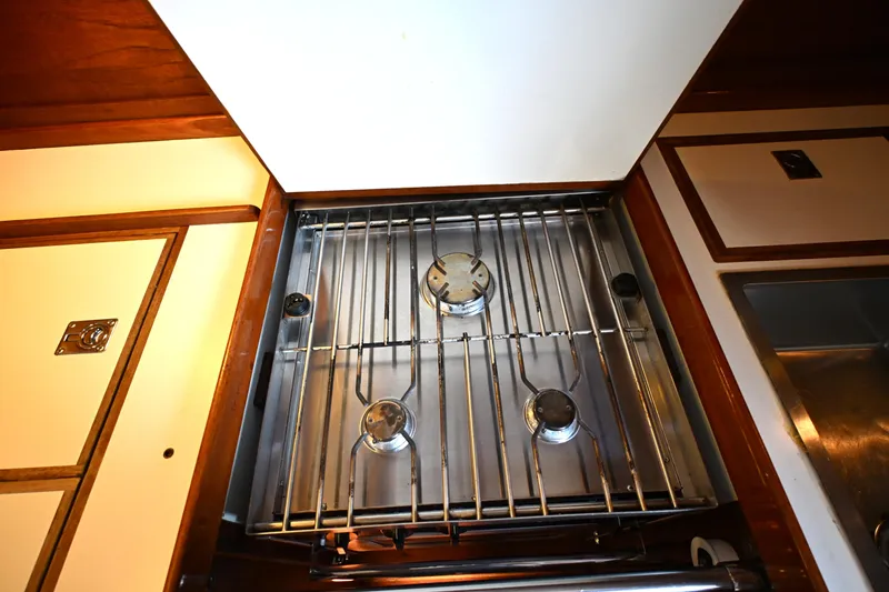 Slide: The Image of Three-burner stove in 1980 Tartan 37 yacht kitchen, surrounded by wooden cabinetry. - 33