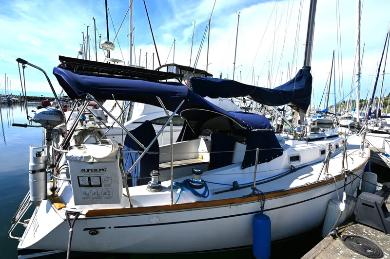 Slide: The Image of 1980 Tartan 37 sailboat docked in a marina, featuring blue covers and lifebuoy. - 5