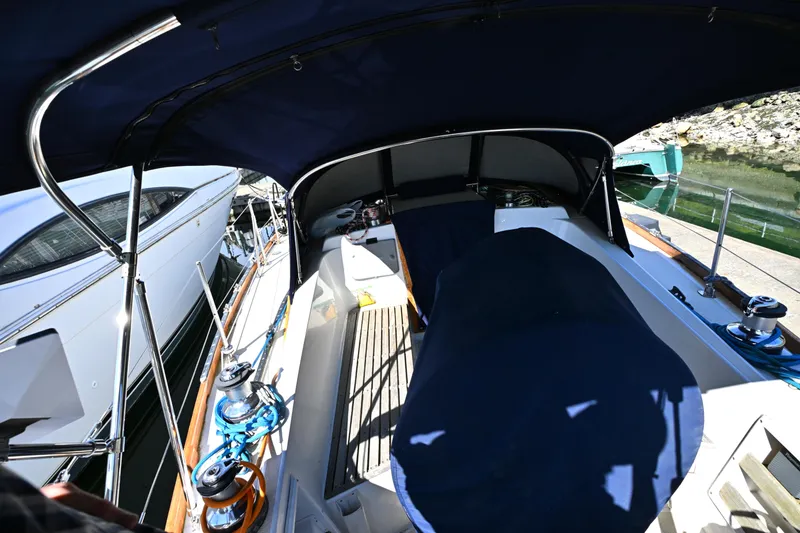 Slide: The Image of 1980 Tartan 37 sailboat cockpit with blue canopy and docked alongside other boats. - 18