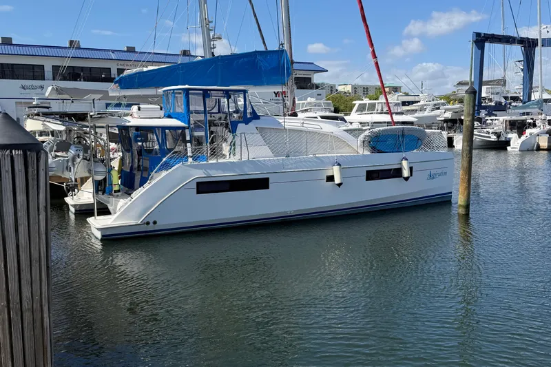 Slide: The Image of 2017 Leopard 40 catamaran docked at marina, featuring blue canopy and modern design. - 2