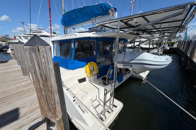 Slide: The Image of 2017 Leopard 40 catamaran docked with dinghy, blue canopy, and wooden pier. - 3