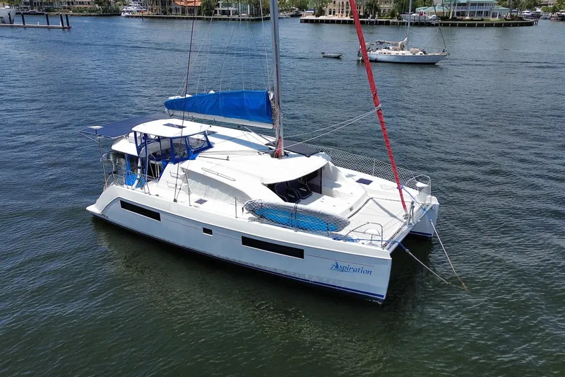 Slide: The Image of 2017 Leopard 40 catamaran with blue sails anchored in a serene harbor. - 37