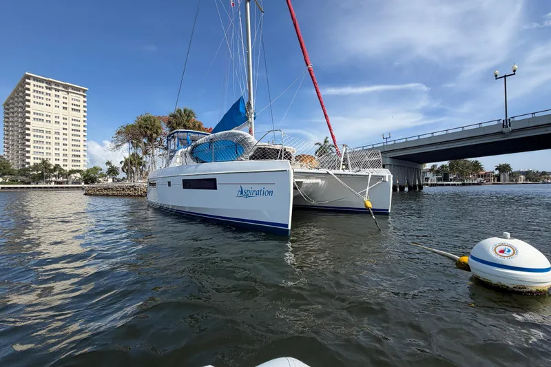 Slide: The Image of 2017 Leopard 40 catamaran moored near a bridge, with a cityscape backdrop. - 40