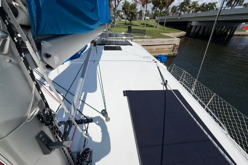 Slide: The Image of 2017 Leopard 40 catamaran deck with solar panels, docked near a bridge and lush greenery. - 64