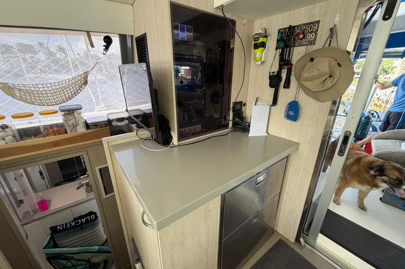Slide: The Image of Interior of a 2017 Leopard 40 catamaran with kitchen counter, storage, and a dog by the door. - 99